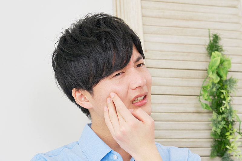 歯が痛くて頬を押さえる男性
